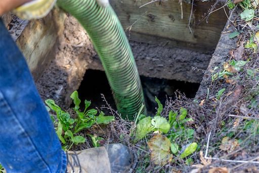 Worker places pump hose into septic system for maintenance services