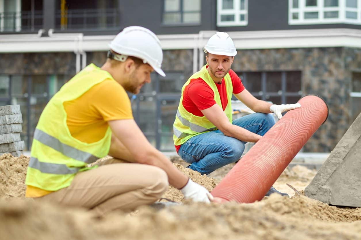 Two certified technicians place drainage for septic system installation